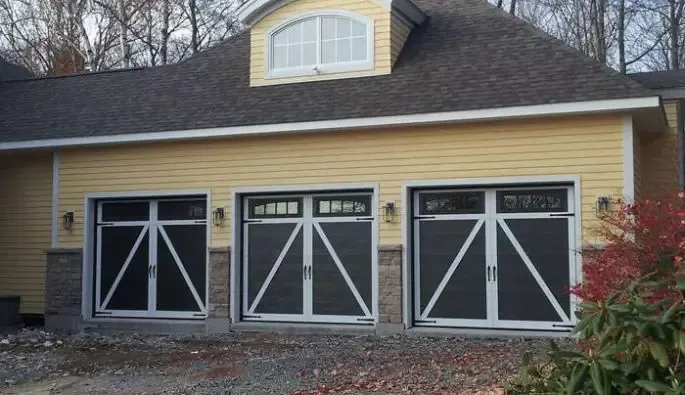 A yellow house featuring three large carriage style garage doors.