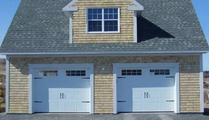 Two garage doors with on a house, set against a clear sky.